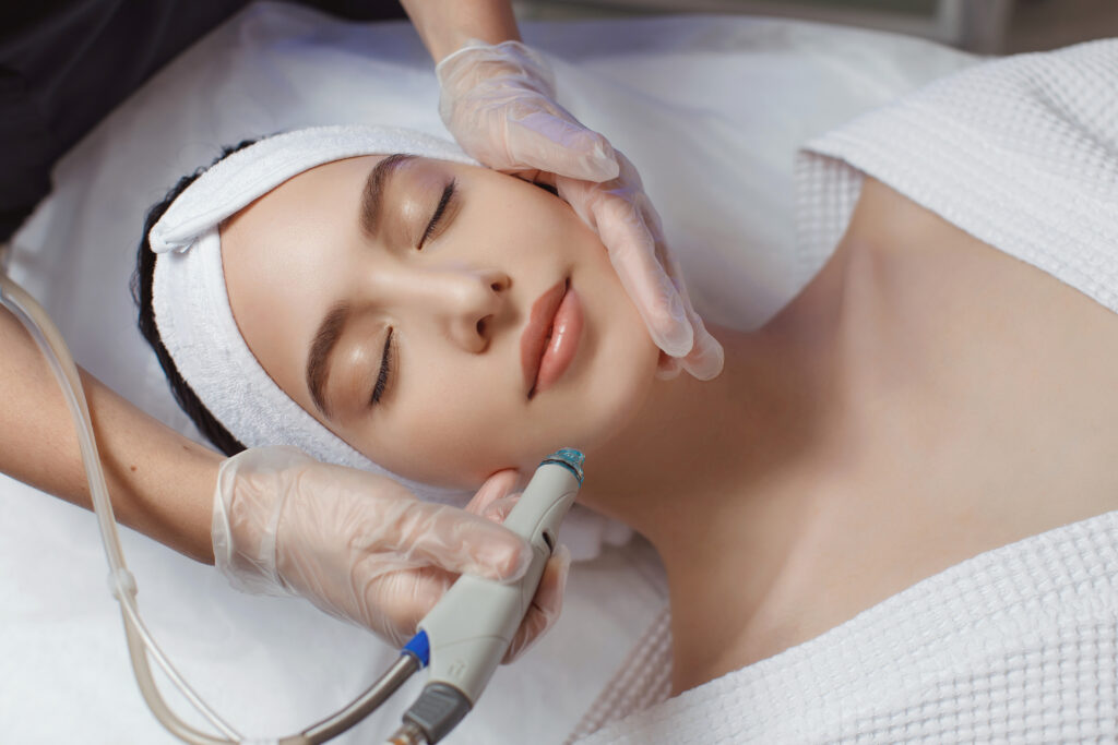side view of woman receiving microdermabrasion therapy on forehead at beauty spa